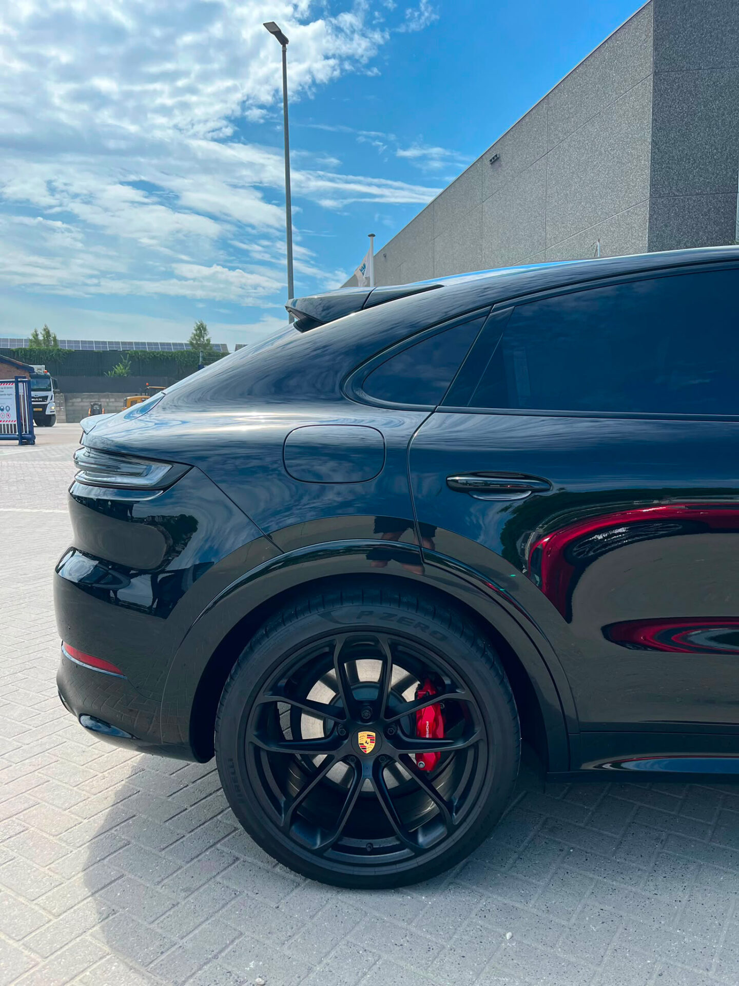 Close-up van het zwarte achterwiel van een Porsche Cayenne S met een rode remklauw en een Porsche-embleem