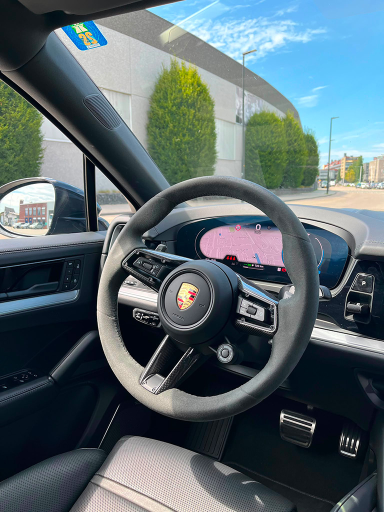 Close-up van het sportstuur met carbon details en het Porsche-embleem in een Porsche Cayenne S